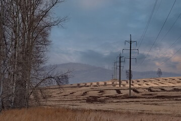 Russia. Krasnoyarsk Territory. Morning view of the relief hills with mown fields in a haze under the sky with picturesque clouds.