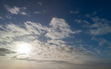 A beautiful sky filled with fluffy clouds against a vibrant blue backdrop, with the sun shining through, creating a serene atmosphere
