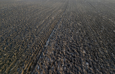 Aerial view of freshly plowed farmland with rich dark soil and textured patterns, showcasing agricultural landscape