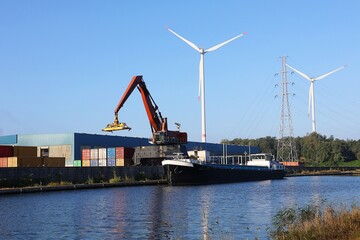 Container crane, containers and barge on the Kempisch Canal, Belgium. Industrial transport via...
