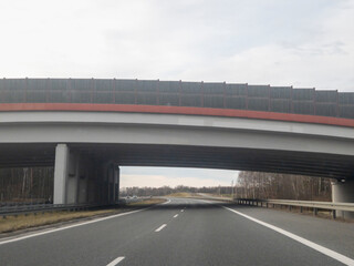 A view of a highway under a modern overpass with a clear sky, showcasing infrastructure and road design.