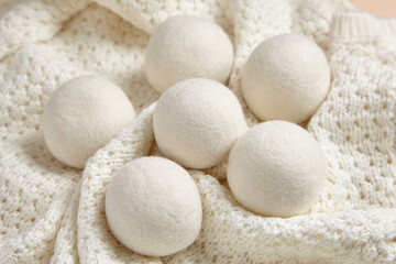 Six wool dryer balls resting on a cozy white knitted blanket. Ideal for eco-friendly laundry, reducing static, and softening clothes naturally