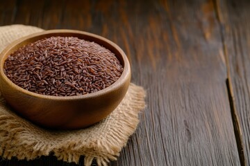 Wooden bowl with red rice on a wooden background