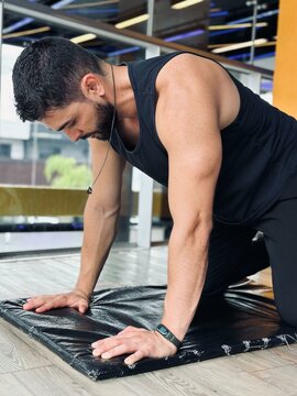 Tired man kneeling on a mat at the gym