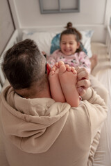 The girl tries not to laugh at the tickling of her feet by her father.