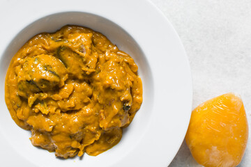 Overhead view of Nigerian owo soup with fish and beef in a white plate, top view of oghwo soup in a large dinner plate, traditional owo soup in a white dish