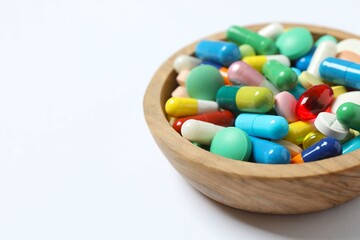 Various pills in a bowl on white background