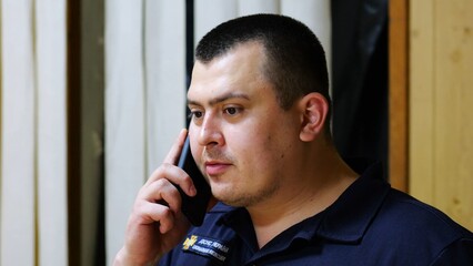 Male firefighter chief have serious telephone conversation with his subordinate by smartphone at...