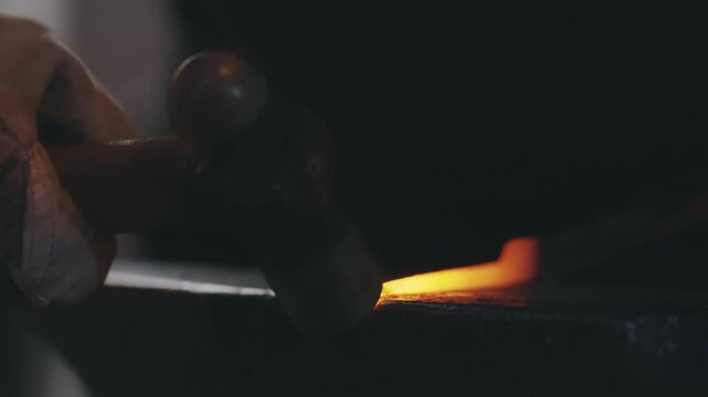Blacksmith hammering glowing metal on an anvil during a forging process