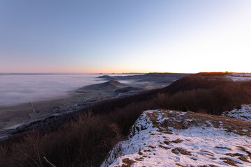 Obraz premium Blick vom Breitenstein, Ochsenwang, Schwäbische Alb auf die drei Kaiserberge - Hohenstaufen, Stuifen und Rechberg. Im Vordergrund die Limburg bei Weilheim Teck im Winter zum Sonnenaufgang mit Nebel.