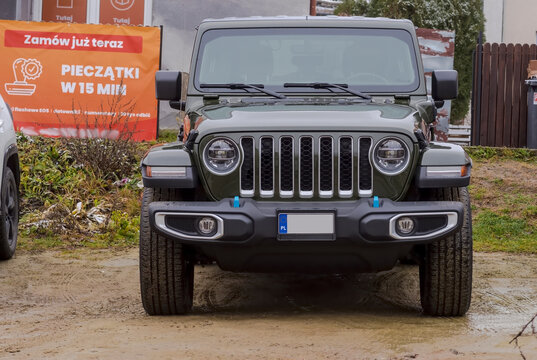 Polska Ostrowiec Świętokrzyski 11 grudnia 2024 12:24. JEEP WRANGLER SAHARA w ciemnozielonym kolorze na błotnistym parkingu. Pojazd terenowy - prawdziwie klasyczna i kultowa marka samochod&oacute;w of - road.