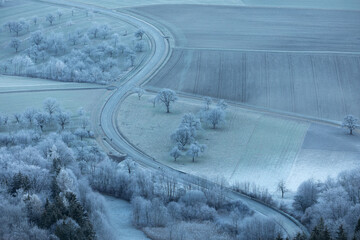 Frost im Tal. Streuobstwiesen bei Bissingen an der Teck. Strasse schlängelt sich die Steige hoch.