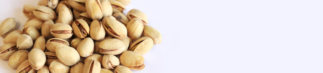 Pistachios on a white background. A handful of dry salted pistachios on a light background, selective focus. Pistachio with shell. Close-up