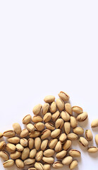 Pistachios on a white background. A handful of dry salted pistachios on a light background, selective focus. Pistachio with shell. Close-up