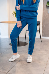 Cute girl model in a sporty comfortable casual blue outfit with a hoodie and sweatpants posing