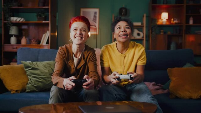 Smiling lesbians hold joysticks enjoying video games