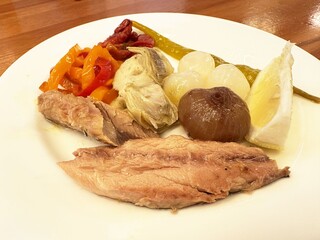 Gourmet plate with sardines, marinated peppers, artichokes, pearl onions, and cheese