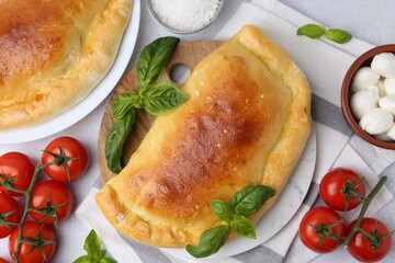 Tasty vegetarian calzones with basil, tomatoes and mozzarella cheese on light table, flat lay