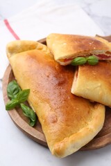 Tasty vegetarian calzones with tomato, cheese and basil on white table, closeup