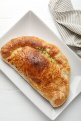 Delicious fresh calzone pizza on white wooden table, top view