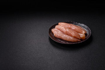 Raw chicken fillet cut into strips with spices and herbs