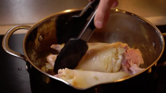 vid&eacute;o en plan fixe avec de la cuisine, autour d'un pied de veau, retournement des deux morceau d'un pied de veaux, avec ustensile de cuisine, retournement difficile car gros et glissant, et la pince t