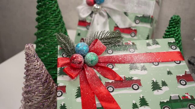 Beautifully wrapped presents adorn a table, surrounded by decorative green trees. The festive atmosphere captures the essence of holiday spirit and gift giving joy.