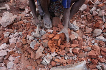 The worker is breaking the bricks into pieces