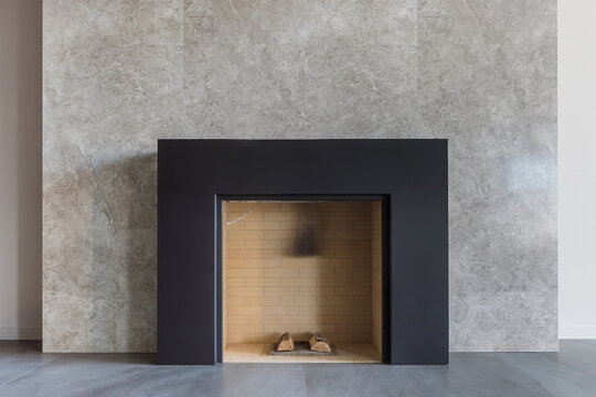 A working fireplace decorated with marble tiles in the interior of a luxurious mansion. .The interior of the fireplace is made of light brick.