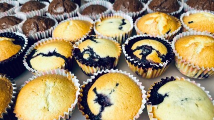 lots of muffins in paper cups, chocolate and with berries, gluten free, stand on a plastic tray. side view. holiday food