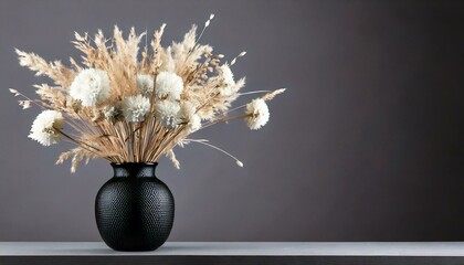 Decorative white dried flowers in a black vase on a dark background