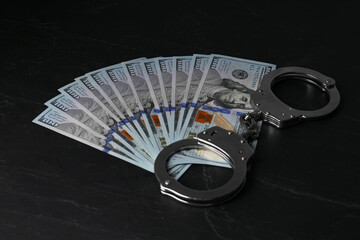 Corruption. Dollar banknotes and handcuffs on black table