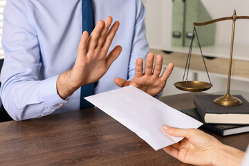 Corruption concept. Woman giving envelope with money to man at wooden table, closeup