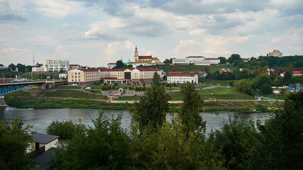 Panoramic view of the city on a sunny summer day. A road bridge crosses the river in the city.