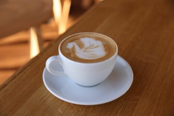 Cup of aromatic coffee on wooden table in cafe, closeup