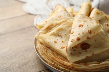 Delicious folded crepes on wooden table, closeup. Space for text