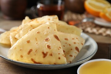 Delicious crepes and honey on wooden table, closeup