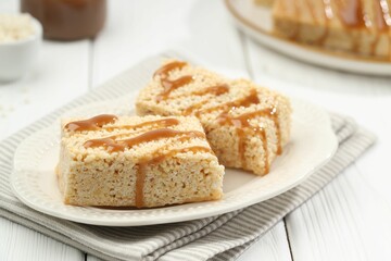 Delicious caramel puffed rice bars on white wooden table, closeup
