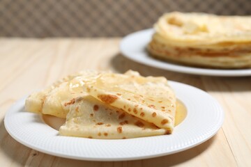 Tasty crepes with honey on wooden table, closeup