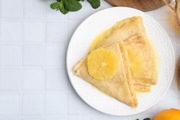 Delicious Crepes Suzette on white tiled table, top view. Space for text
