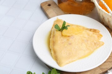Tasty crepes Suzette on white tiled table, closeup. Space for text