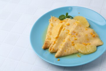 Tasty crepes Suzette on white tiled table, closeup. Space for text