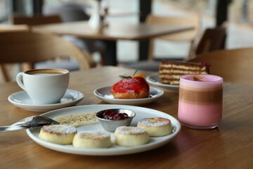 Delicious cottage cheese pancakes, desserts and aromatic coffee served on wooden table in cafe