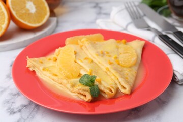 Plate with tasty crepes Suzette on white marble table, closeup
