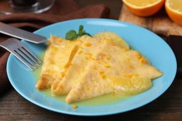 Plate with tasty crepes Suzette on wooden table, closeup
