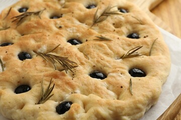 Delicious focaccia bread with olives and rosemary on table, closeup