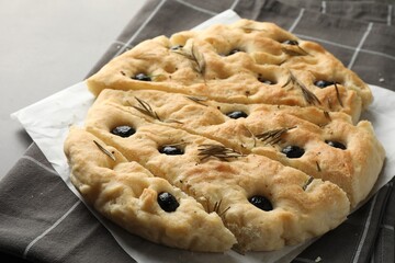 Slices of delicious focaccia bread with olives and rosemary on grey table, closeup