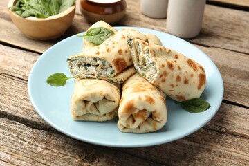 Tasty rolled crepes with cottage cheese and spinach served on wooden table, closeup