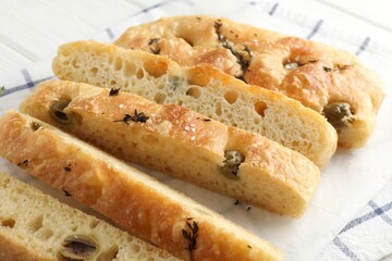 Slices of delicious focaccia bread with olives, thyme and salt on table, closeup