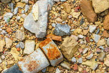 An old rubber hose for the hydraulic system drive against a background of stones and broken bricks.